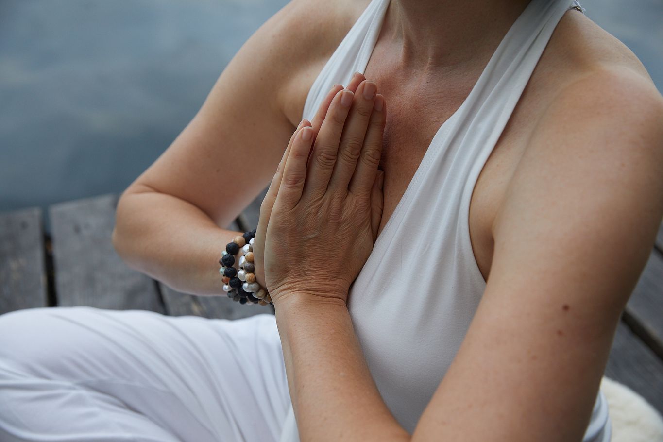 Kundalini Yoga Mediation Entspannung Tagesretreat, Frau in schlichter weißer Kleidung in Meditationshaltung auf hölzernem Steg am See, Maschsee Sonnenaufgang