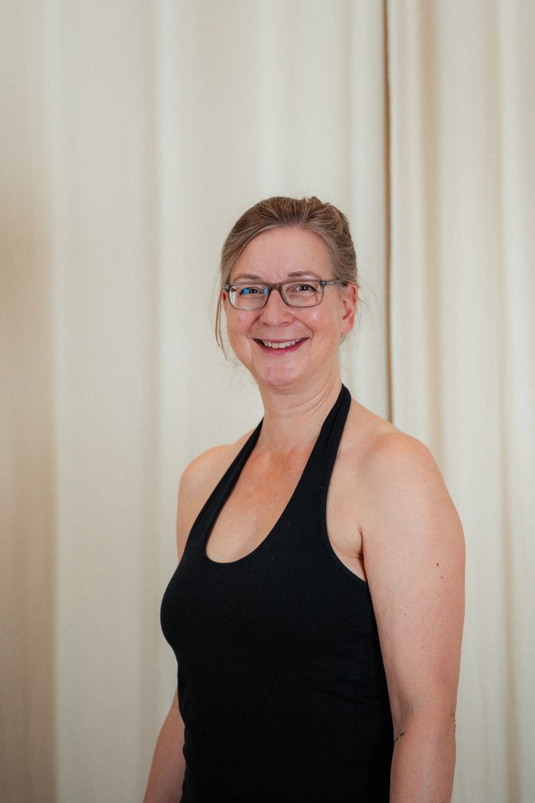 Portrait Prem Jaijeet Kaur von Kundalini Yoga Mediation und Entspannung in Hannover - auf Sofa sitzend in weißem Kleid mit Grünpflanze im Hintergrund